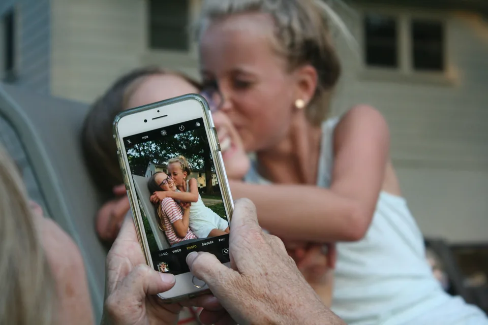 Una madre fotografía con el móvil a sus hijas mientras se abrazan en una reunión familiar