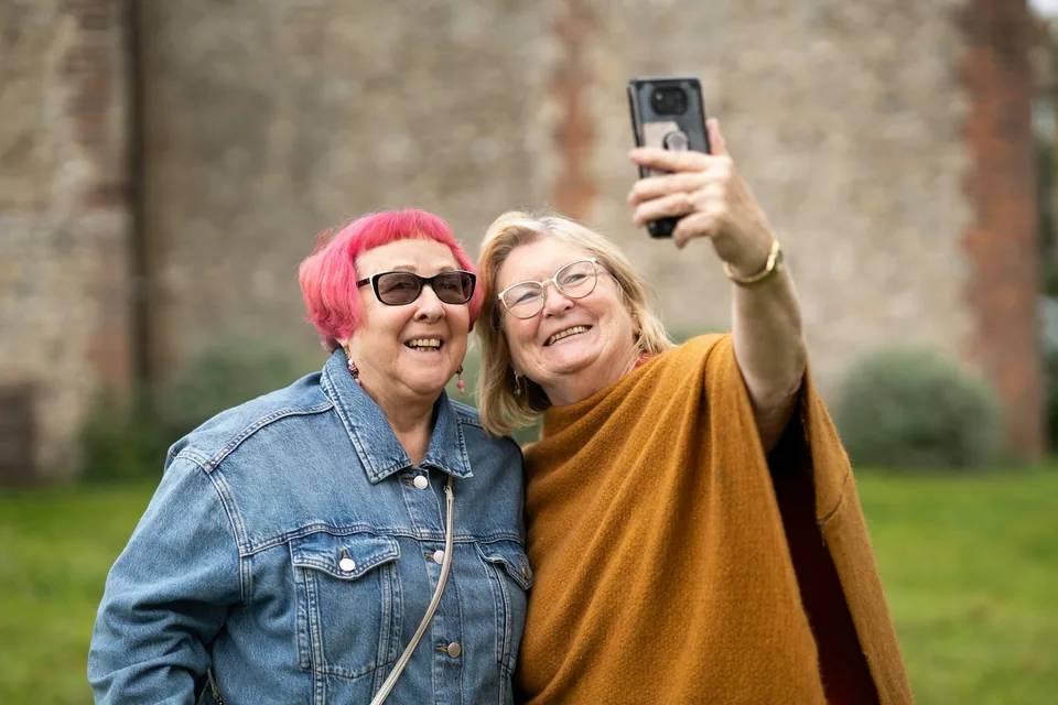 Dos mujeres mayores se hacen un selfie sonriendo al aire libre