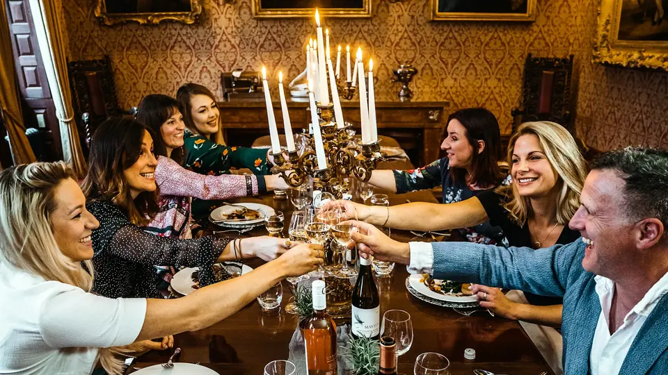 Amigos brindan alrededor de una mesa con velas durante una cena de cumpleaños