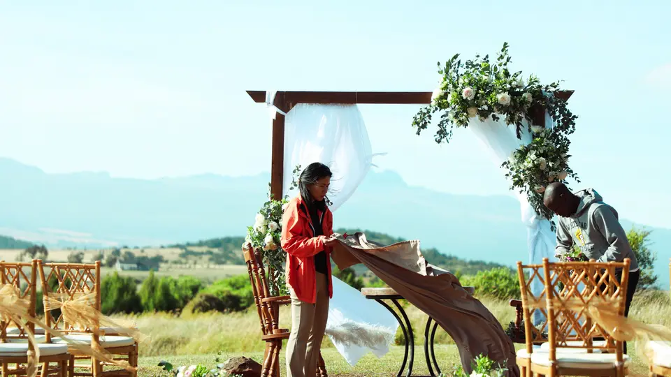 Dos profesionales montan el arco floral y las sillas de una ceremonia al aire libre