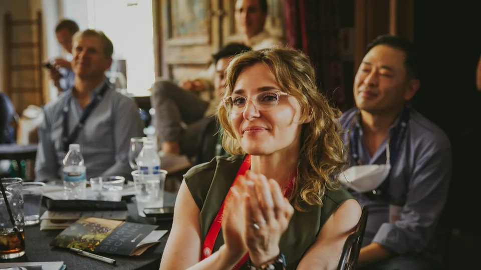 Una asistente aplaude sonriente durante una cena de un evento de empresa