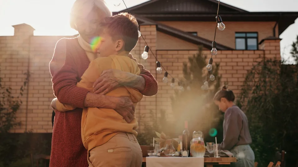 Una abuela abraza a su nieto en una comida familiar al aire libre