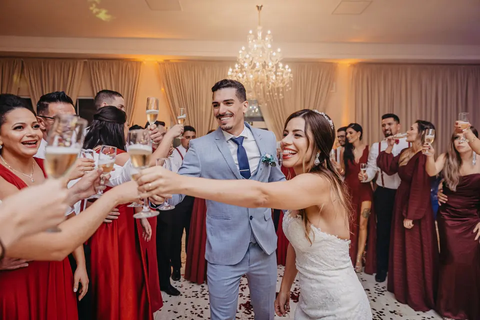 Los novios brindan en el salón del banquete mientras sus invitados levantan las copas hacia ellos