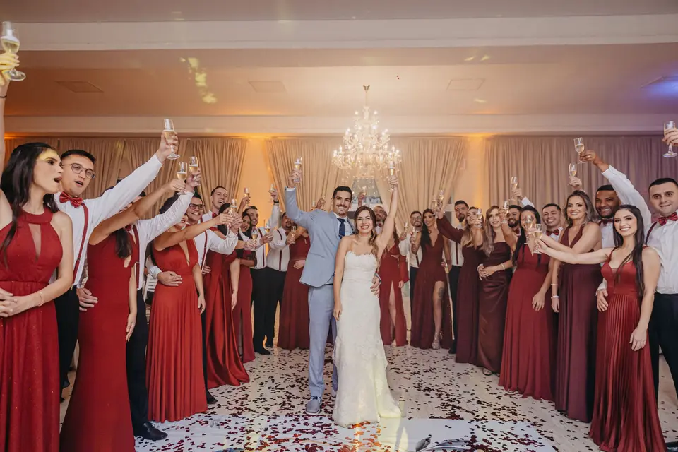 Los novios, en el centro de un corro de invitados que levantan sus copas en el salón del banquete