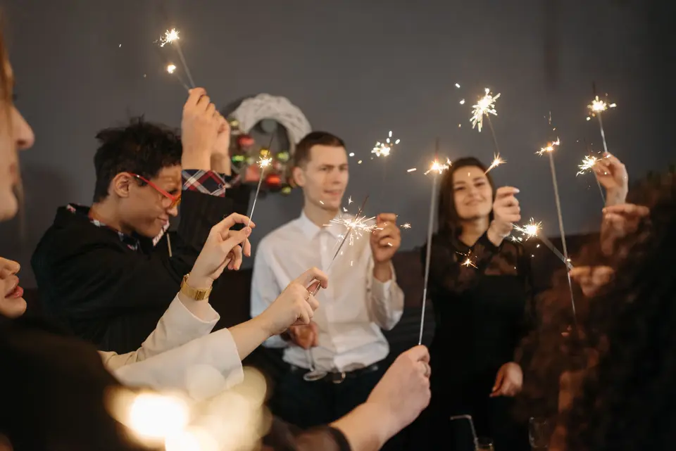 Compañeros de la oficina brindan con copas y bengalas durante la fiesta de fin de año