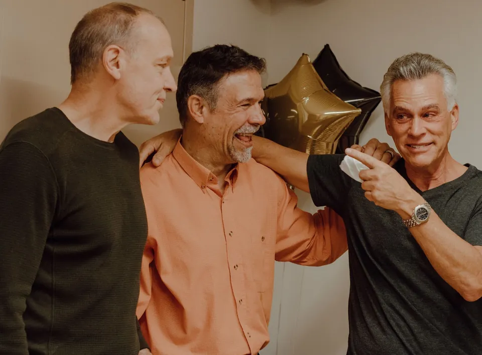 Tres compañeros de trabajo ríen juntos en una fiesta de jubilación