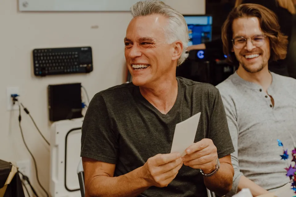 Un hombre que se jubila lee sonriendo una tarjeta de sus compañeros durante la despedida