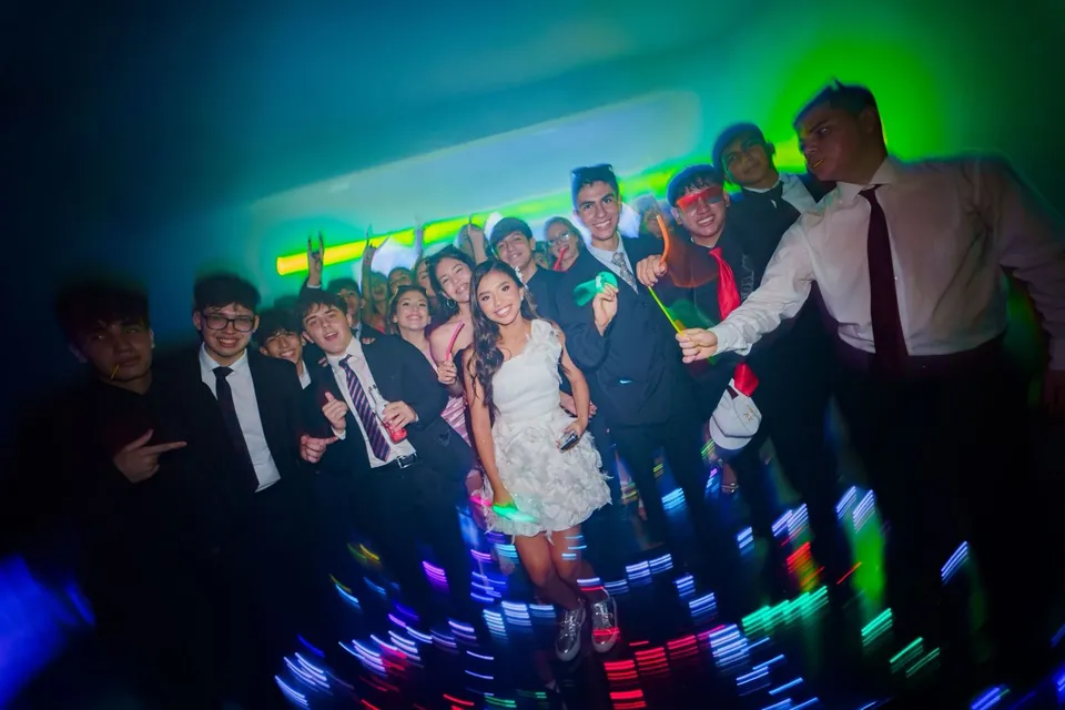 Los amigos bailan con la quinceañera en la pista, con luces de colores
