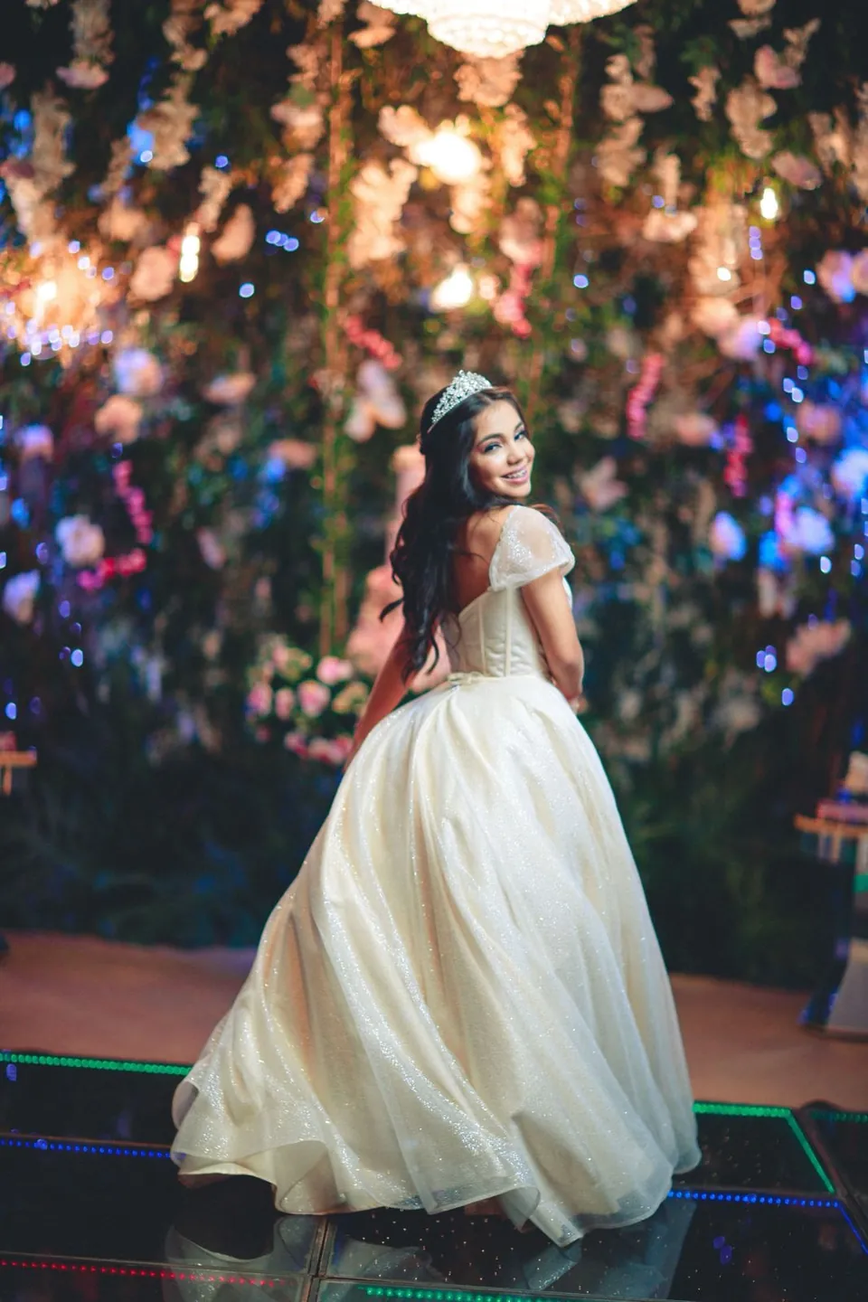 La quinceañera sonríe a cámara mientras gira su vestido blanco
